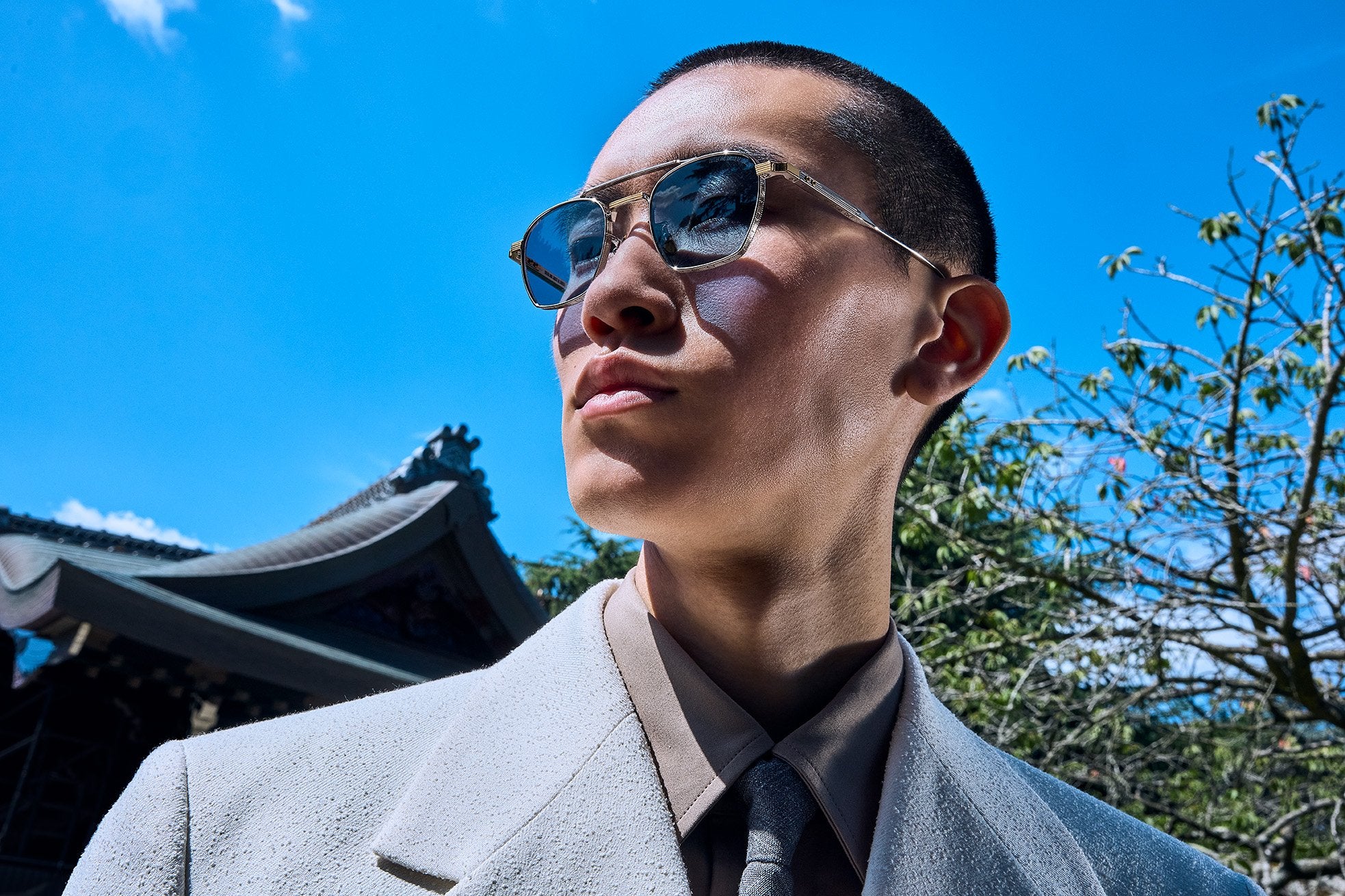 Model wearing Cutler and Gross designer sunglasses in an outdoor campaign portrait under bright sunlight