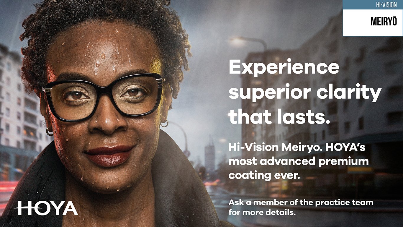 person wearing glasses with a blurred city street background and HOYA advertisement text.